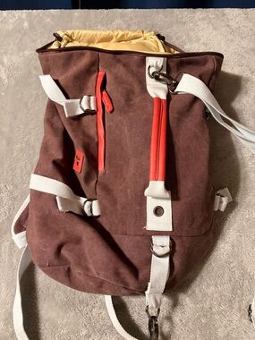 Brown Canvas Roll-Top Backpack with White Straps and Red Trim